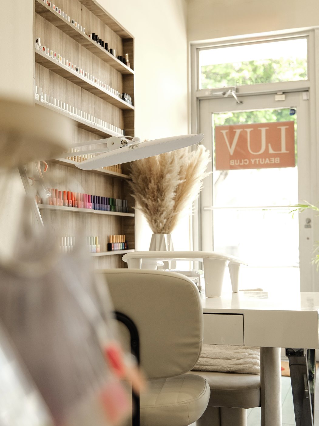 Inside LUV Beauty Club nail salon in Miami with manicure station and polish wall